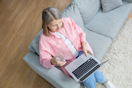 Top view of a woman sitting on the sofa with a laptopの写真素材