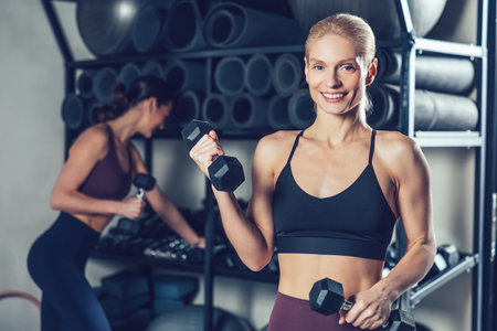 Fit and sporty young caucasian women with dumbbells in the gymの写真素材