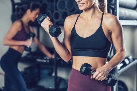 Fit and sporty young caucasian women with dumbbells in the gymの写真素材