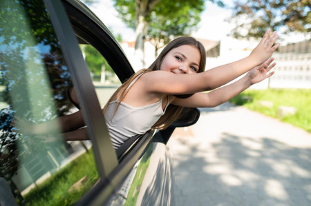 Schoolgirl sitting in car seat enjoying summer trip on highwayの写真素材