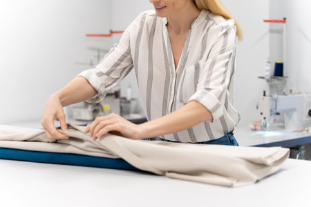 Fashion designer holding fabric in hands while working in design studioの写真素材