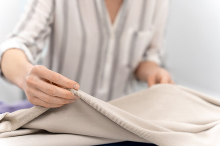Fashion designer holding fabric in hands while working in design studioの写真素材