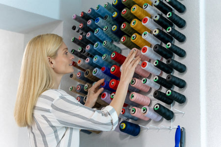 Blonde caucasian female fashion designer choosing threads for sewingの写真素材