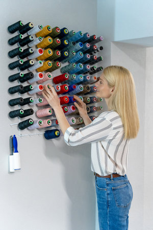 Blonde caucasian female fashion designer choosing threads for sewingの写真素材