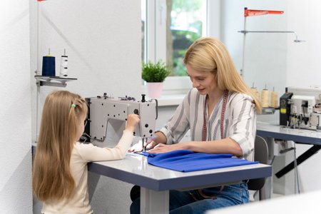 Blonde long-haired female dress designer in her studio with her daughterの写真素材