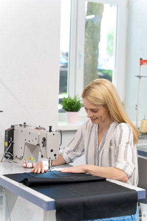 Female designer sitting at the sewing machine and looking involvedの写真素材