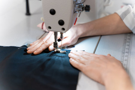 Close up of female hands holding fabric while sewingの写真素材