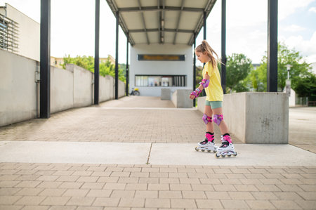 Little female skater riding roller-blades outdoors having funの写真素材