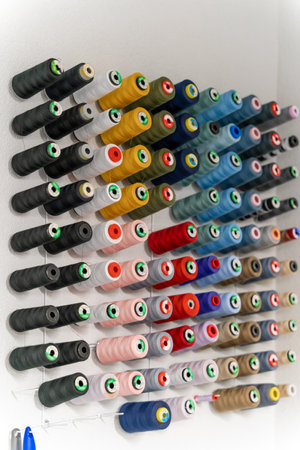 Many colorful threads and balls of wool in a row on the wallの写真素材