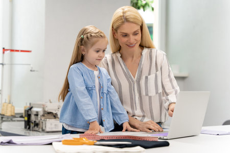 Pretty young caucasian woman in her design studio with her daughterの写真素材