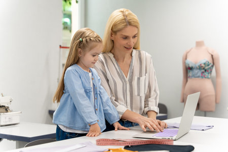 Pretty young caucasian woman in her design studio with her daughterの写真素材