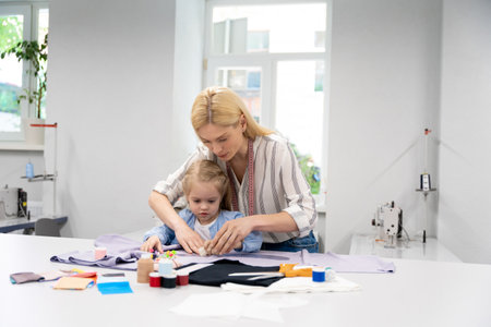 Mom and daughter cutting out anew model and looking involvedの写真素材