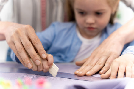 Mom and daughter cutting out anew model and looking involvedの写真素材