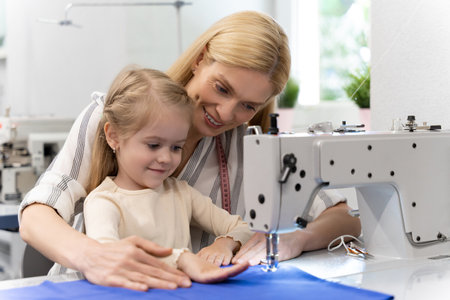 Mom and kid in a dress design studio working together on a new collectionの写真素材
