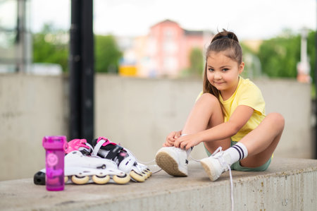 Female child putting on roller-blades getting ready for energetic playの写真素材