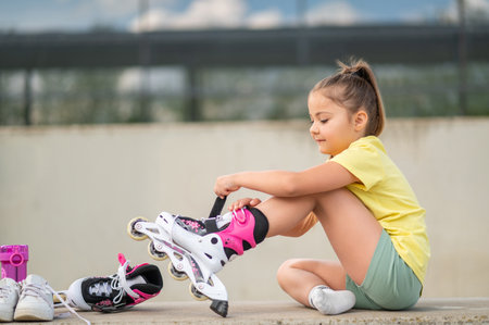 Female child putting on roller-blades getting ready for energetic playの写真素材
