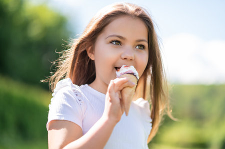 Happy female child eating delicious ice cream on warm summer dayの写真素材