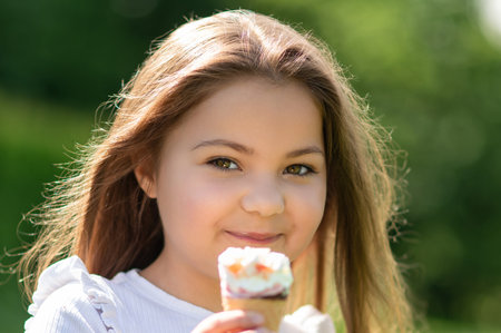 Happy female child in summer eating ice cream on hot dayの写真素材