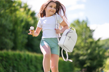 Happy little girl running outside holding delicious waffle cone enjoying cool ice creamの写真素材