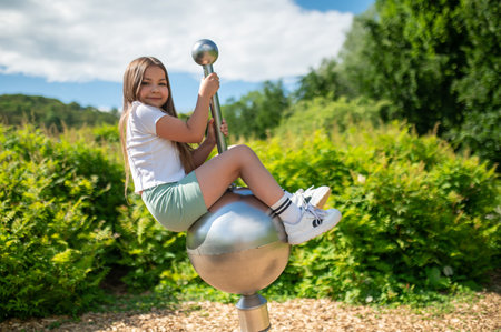 Happy child girl playing on sunny summer day enjoying swingingの写真素材