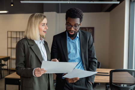 African american lawyer looking surprised while checking the documents his colleague showing him