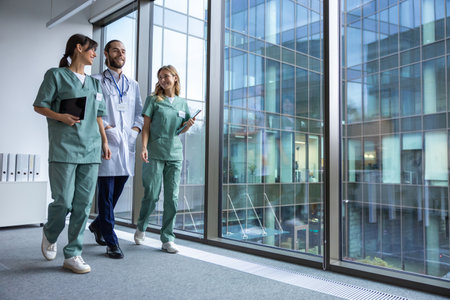 Group of young doctors in lab coats walking in the clinic corridor and talkingの写真素材