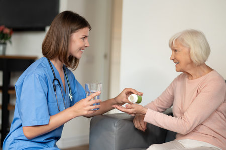 Nurse in uniform offering health support and nursing care to elderly patient in retirement homeの写真素材