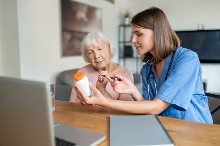 Nurse explaining elderly woman patient medications on laptop in medical clinic or in hospice careの写真素材