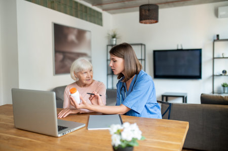 Nurse taking care of disabled senior elderly woman using laptop computer togetherの写真素材