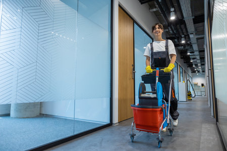 Dark-haired young woman in uniform with a cart of cleaning equipment