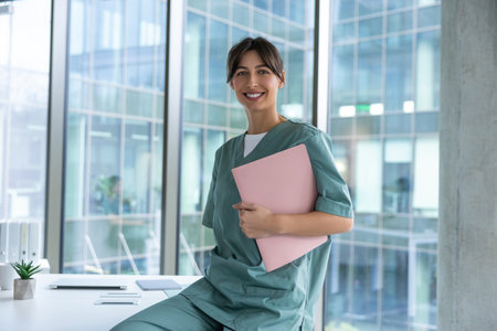 Smiling dark-haired female doctor in lab coat with a medical history in handsの写真素材