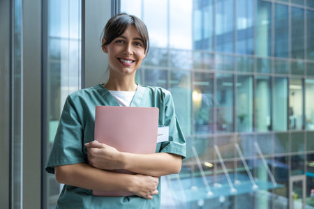 Smiling dark-haired female doctor in lab coat with a medical history in handsの写真素材