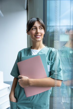 Smiling dark-haired female doctor in lab coat with a medical history in handsの写真素材