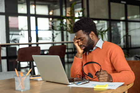 African american entrepreneur looking tired after hours of overtimeの写真素材