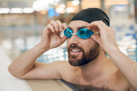 Smiling bearded caucasian young man putting on swimming glassesの写真素材