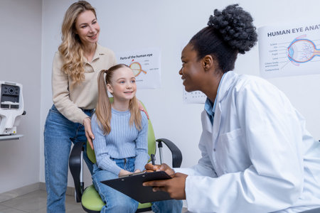 Fair-haired girl and her mom having consultation at the ophthalmologist officeの写真素材