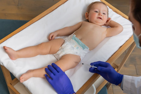 Cute baby boy lying on a table while doctor making vaccination to himの写真素材