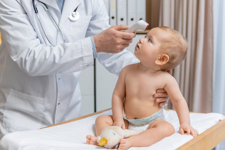 Pediatrician measuring temperature of a little baby boy during the check upの写真素材