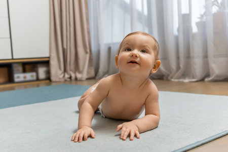Cute little baby boy crawling on the floor and looking contentedの写真素材