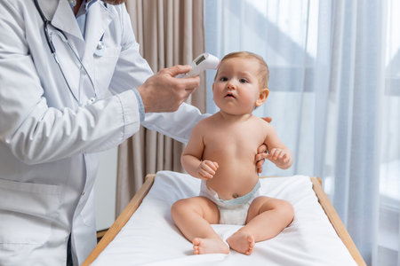 Pediatrician measuring temperature of a little baby boy during the check upの写真素材
