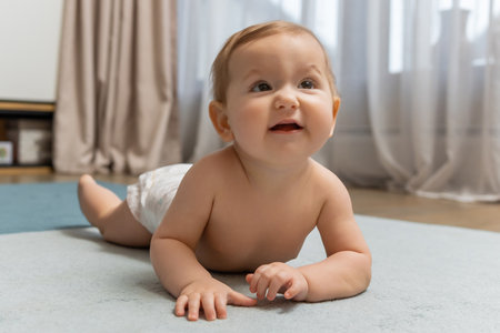 Cute little baby boy crawling on the floor and looking contented