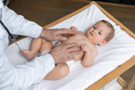 Doctor examining a little baby boy in his office and looking concentratedの写真素材