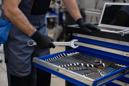 Mechanic with toolbox and laptop in workshop