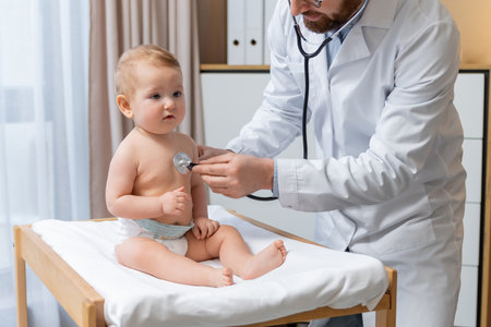 Doctor holding a stethoscope and listening to the babys heartbeatの写真素材