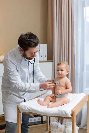 Doctor holding a stethoscope and listening to the babys heartbeatの写真素材
