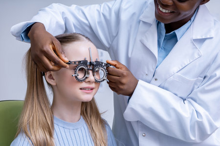 Doctor adjusting optometric tool while testing vision of a girlの写真素材
