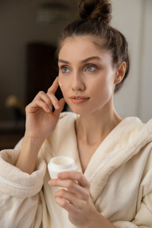 Brown haired woman taking care of her face with creamの写真素材