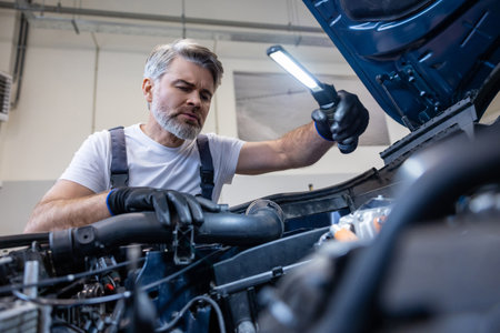 Mechanic using flashlight on engineの写真素材