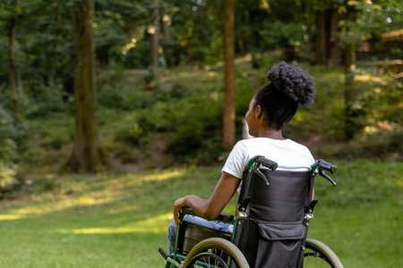 African american young woman on a wheelchair in the parkの写真素材