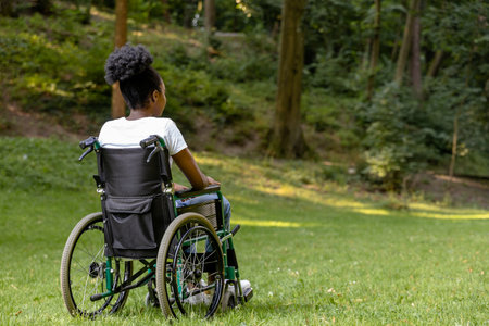African american young woman on a wheelchair in the parkの写真素材